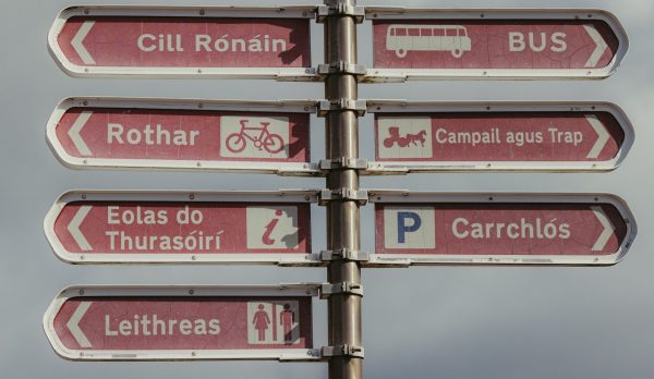 A multilingual fingerpost sign against open sky
