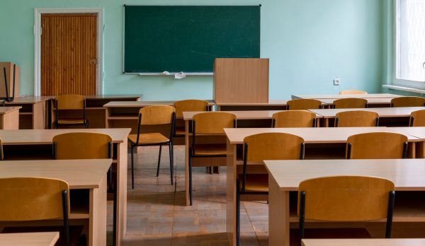 An empty classroom with wooden desks and a chalkboard