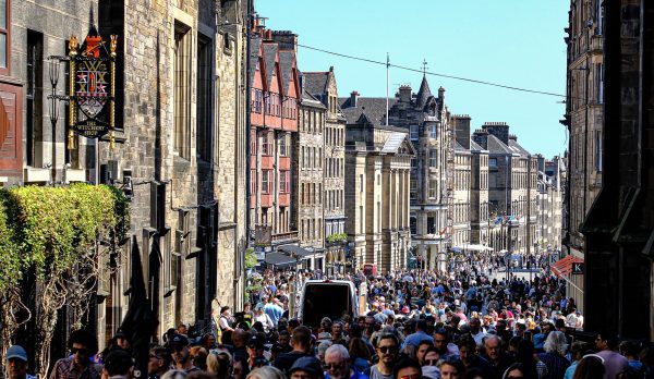 A crowded street of visitors in Edinburgh on a sunny day