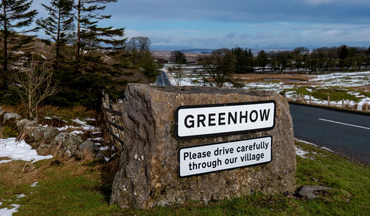 A village welcome sign beside a snowy road
