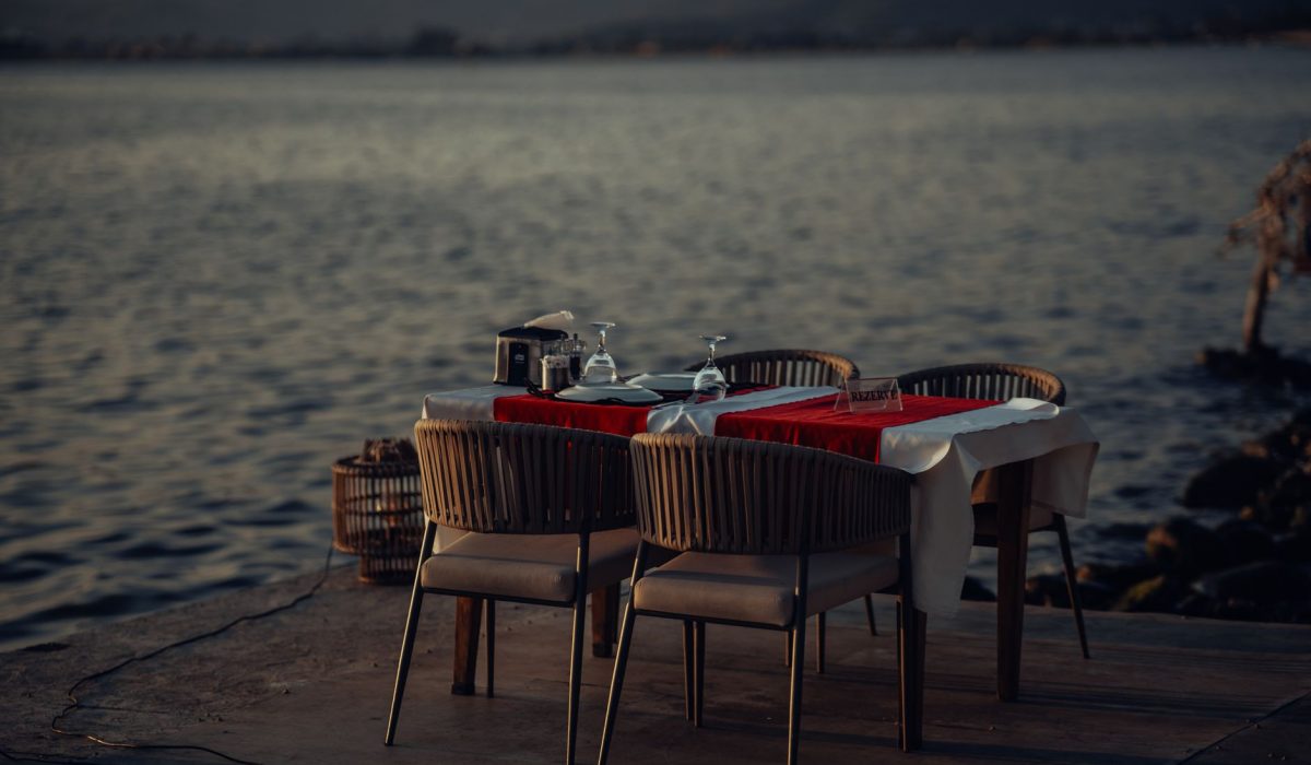 A dining table set by the sea at sunset