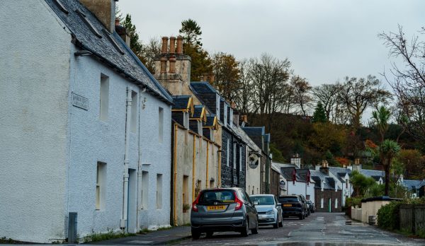 A village street of stone cottages with parked cars