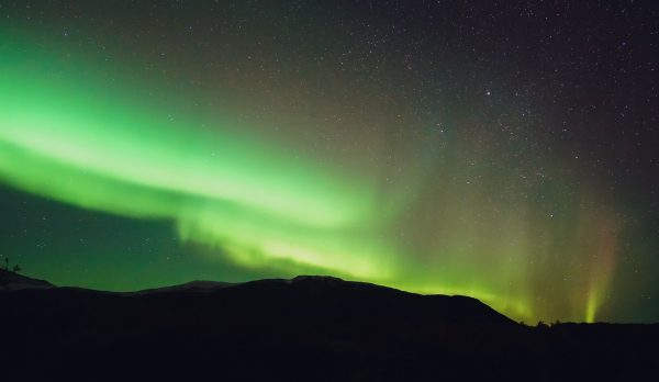 The aurora over a dark mountain silhouette