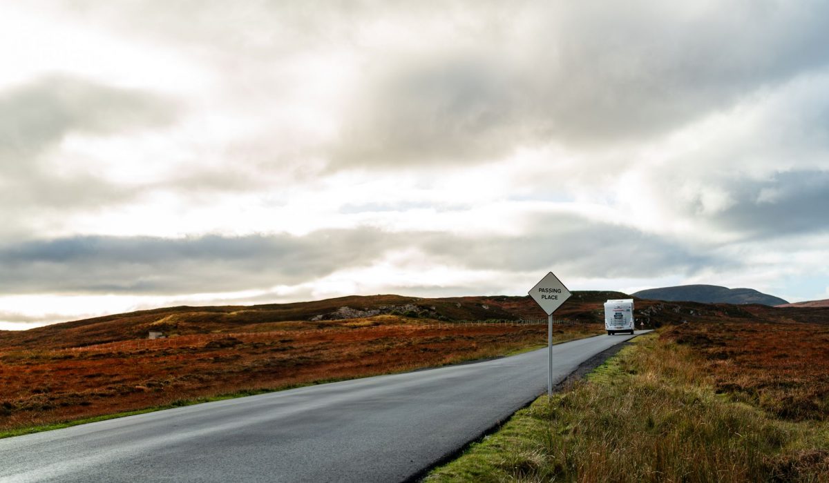 A caravan on a road through autumn scenery