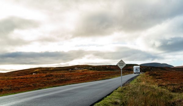 A caravan on a road through autumn scenery