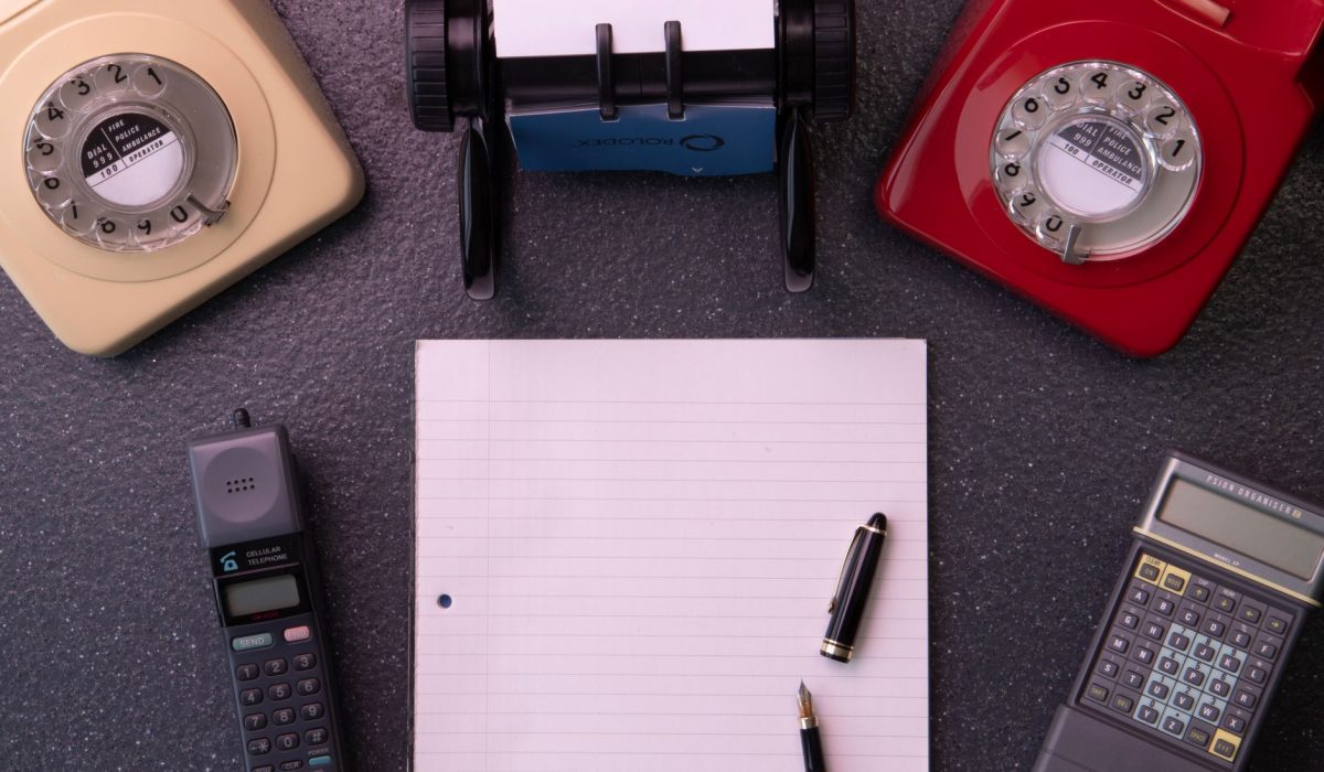 A rotary telephone beside an open notebook